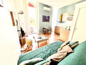 a living room with a green couch and a table at ApartHotel Riviera - Grimaldi Coeur de Ville - Large Studio AC with bigger South Terrace - Hyper Centre - TERRASSE ESPRIT in Nice +4 photos