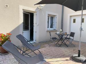 a patio with chairs and an umbrella and a table at Studio cosy in Mende