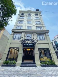 a tall white building with a sign on it at Moma Paris Hotel Ninh Bình in Ninh Binh