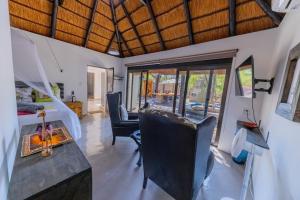 a room with a bed and a desk and chairs at African Sky Villas in Marloth Park