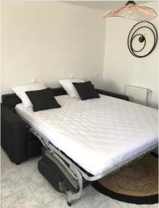 uma cama branca com almofadas pretas num quarto em Studio cosy em Mende