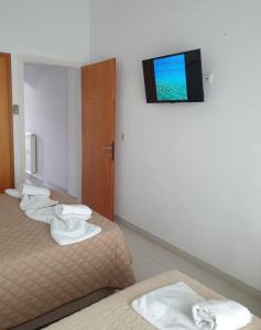 a hotel room with two beds and a flat screen tv at PANSION ALEXANDROS BY THE SEA in Nea Skioni