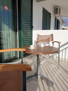a wooden table and a chair on a balcony at PANSION ALEXANDROS BY THE SEA in Nea Skioni