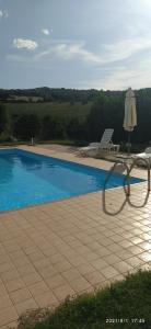 une chaise et un parasol à côté de la piscine dans l'établissement LA TANA DEL CINGHIALE, à Santa Vittoria in Matenano