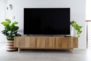 een flatscreen-tv op een houten standaard in een woonkamer bij Serenity Cove luxe retreat in Maroochydore