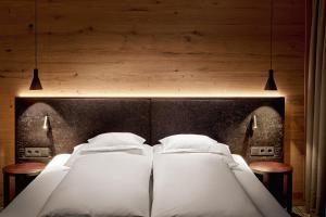 two beds in a bedroom with two lights on the wall at Hotel Auenhof in Lech am Arlberg