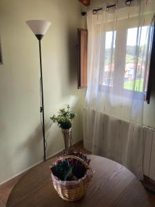 a table with a basket and a lamp and a window at La Canal in Ubiarco