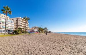 einen Strand mit Palmen und Gebäuden und dem Meer in der Unterkunft Awesome Apartment In La Cala Del Moral With Kitchenette in La Cala del Moral