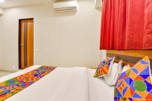 a bedroom with a bed with colorful sheets and pillows at FabHotel Happinex in Surat