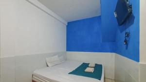 una camera blu e bianca con un letto con un asciugamano sopra di Reddoorz @ Homestay Gayatri a Malang