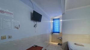 baño con aseo y TV en la pared en Reddoorz @ Homestay Gayatri en Malang