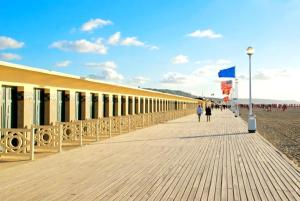 a boardwalk on a beach with people walking on it at Appartement Marina magnifique vue in Deauville