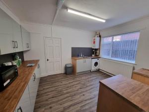 a kitchen with white cabinets and a wooden floor at 70 Southfield in Middlesbrough