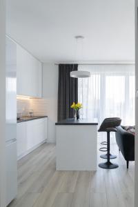 a kitchen with white cabinets and a table with flowers on it at Apartament Green Lake - Mrągowo in Mrągowo