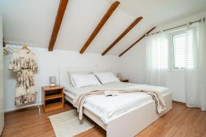 a white bedroom with a bed and a window at Apartment Sunday in Mokošica