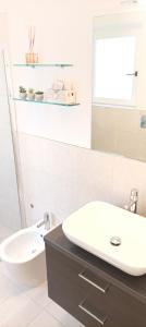 a white bathroom with a sink and a mirror at La casina di Ale in Marina di Carrara