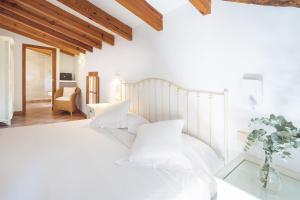 a white bedroom with a large bed with white pillows at Es Nord in Estellencs