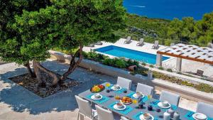 Una mesa con comida al lado de una piscina. en A gorgeous villa on a private property on the island Brač, en Pučišća