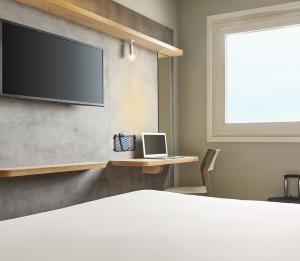 Habitación con cama y ordenador portátil en una mesa en ibis budget Paris Porte d'Aubervilliers, en Aubervilliers