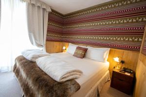 a bedroom with a bed with a red wall at Hotel Bucaneve in Breuil-Cervinia