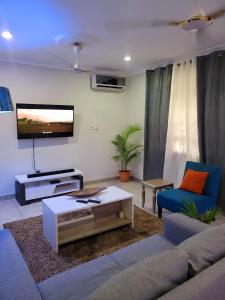 a living room with a couch and a tv at Kojosvilla Ground floor in Kwedonu