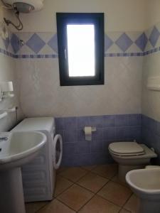 bagno con lavandino, servizi igienici e finestra di Residence Edilmare San Teodoro a San Teodoro