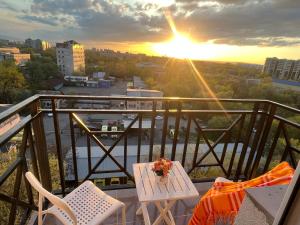 uma varanda com mesa e cadeiras e o pôr-do-sol em Студия в центре города, в «Золотом квадрате» em Almaty