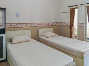 twee bedden naast elkaar in een kamer bij RedDoorz Syariah near Pasar Sleko Madiun in Madiun