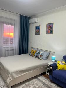 um quarto com uma cama e um sofá azul em Студия в центре города, в «Золотом квадрате» em Almaty
