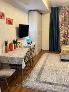 uma sala de estar com uma mesa e cadeiras e uma televisão em Студия в центре города, в «Золотом квадрате» em Almaty