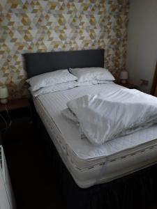 Una cama con sábanas blancas y almohadas. en 6 BERTH DELUXE CARAVAN PG73 GOLDEN PALM, en Chapel St. Leonards