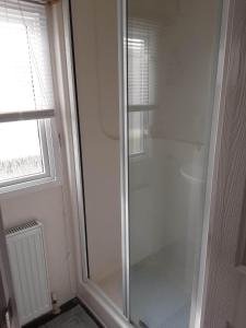 a glass shower in a bathroom with a window at 6 BERTH DELUXE CARAVAN PG73 GOLDEN PALM in Chapel Saint Leonards