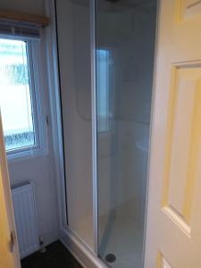 a glass shower in a bathroom with a window at 6 BERTH DELUXE CARAVAN PG73 GOLDEN PALM in Chapel Saint Leonards