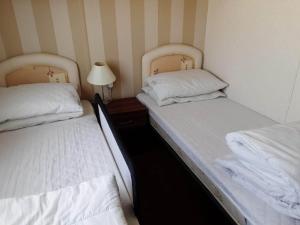 two beds in a small room with white sheets at 6 BERTH DELUXE CARAVAN PG73 GOLDEN PALM in Chapel Saint Leonards