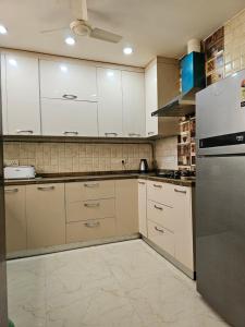a kitchen with white cabinets and a refrigerator at Hostmystay- 3Bhk Terrace! Gk1 M block in New Delhi