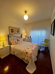 een slaapkamer met een bed, een lamp en een stoel bij Cocas House II - Almada in Almada