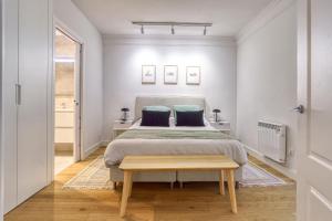 a white bedroom with a bed and a table at TRIUNFO SUITE by Sweet Home San Sebastian in San Sebastián