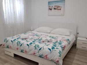 um quarto com uma cama com colcha floral em Apartmani Pina 2 em Kaštela