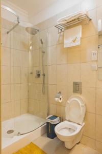 a bathroom with a shower and a toilet and a tub at The Avery Apartments, Dzorwulu in Accra