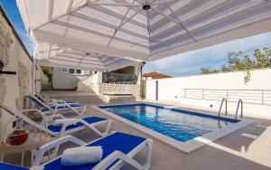 a patio with a pool and an umbrella and chairs at Villa Sunrise in Lopar