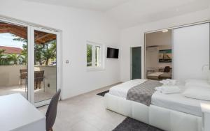 a white bedroom with a bed and a table and a desk at Villa Sunrise in Lopar +24 photos