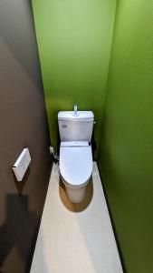 een badkamer met een wit toilet in een groene muur bij 富士吉田たまきや in Fujiyoshida