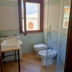 a bathroom with a toilet and a sink and a window at Santa Teresa Gallura Green House in Santa Teresa Gallura