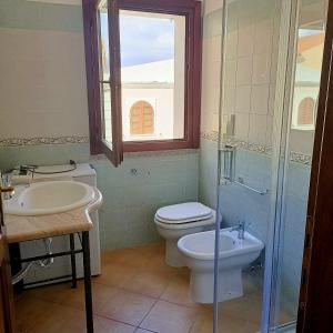 une salle de bain avec toilettes, lavabo et fenêtre dans l'établissement Santa Teresa Gallura Green House, à Santa Teresa Gallura