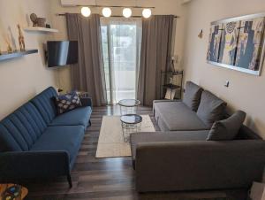 Cozy apartm.near Metro Ag.Marina في أثينا: غرفة معيشة مع كنبتين زرقاوين وطاولة