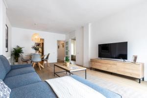sala de estar con sofá azul y TV de pantalla plana en Exclusive Apartments Barcelona 4 personas Torrella, en Terrassa
