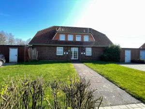 a red brick house with a grass yard at Ferienwohnung direkt am Deich - Seerobbe - in Dornum