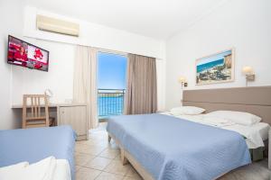 a hotel room with two beds and a desk and a window at Aristea Hotel in Elounda