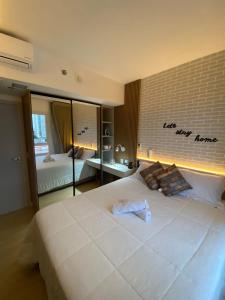 a bedroom with a large white bed with a brick wall at Conforto no melhor do Marista & Goiânia in Goiânia