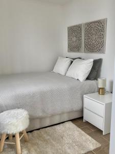 Dormitorio blanco con cama y mesa blanca en Alojamento confortável a 2 min da Praia en Horta